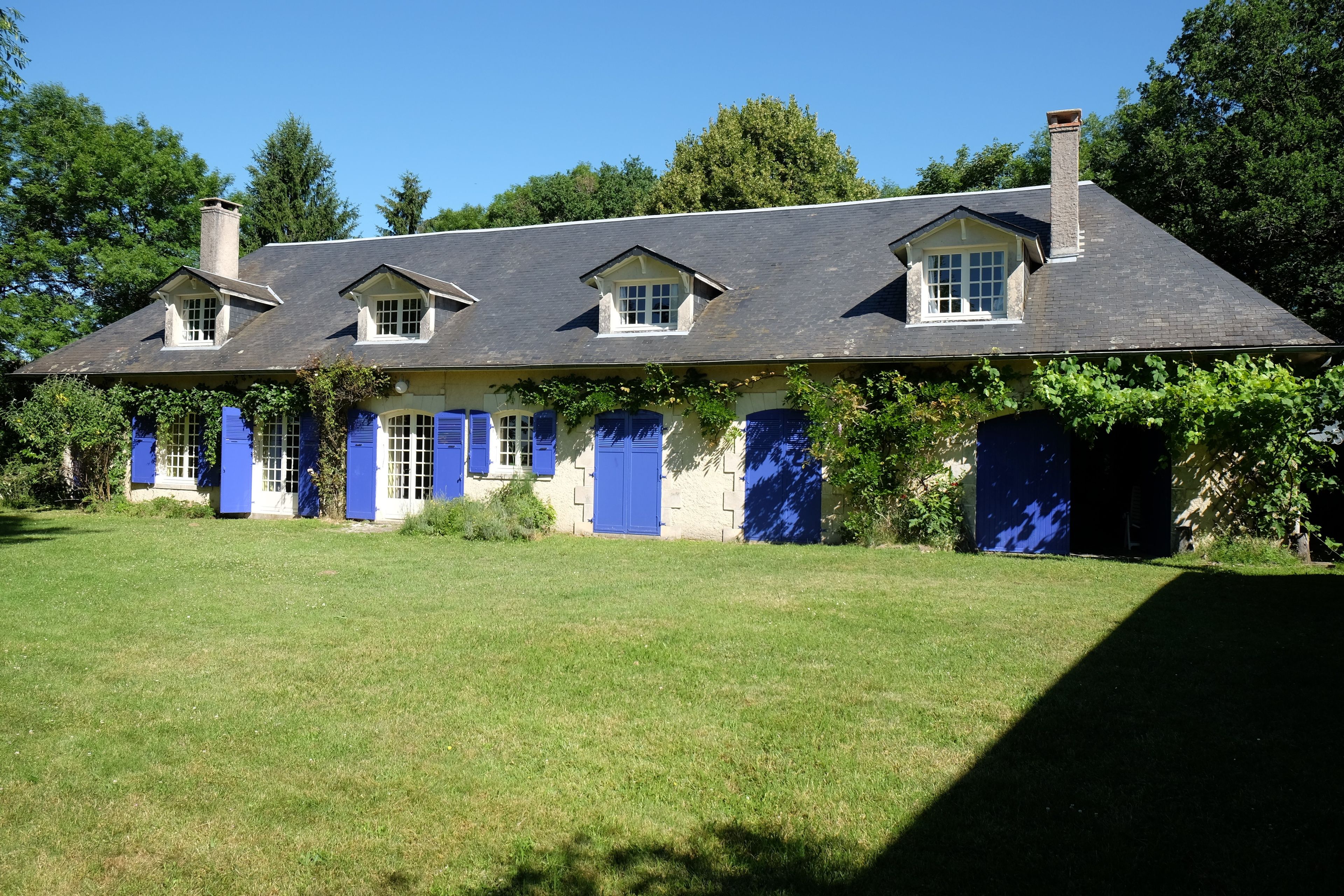 A two-story house with a sloped roof, multiple windows, and blue shutters.