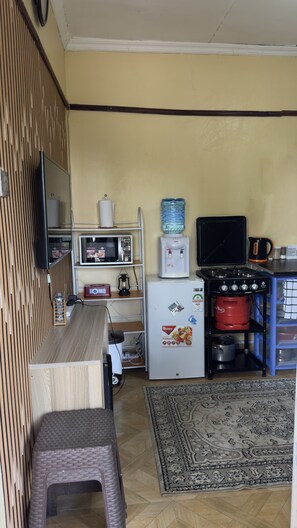 Une cuisine compacte équipée d’un réfrigérateur, d’un four à micro-ondes, d’un distributeur d’eau et d’une cuisinière.
