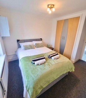 A hotel room with a bed, a nightstand, a lamp, a wardrobe, and a radiator.