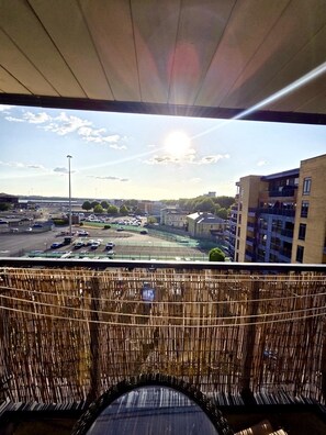 A balcony with a view of a parking area and buildings.