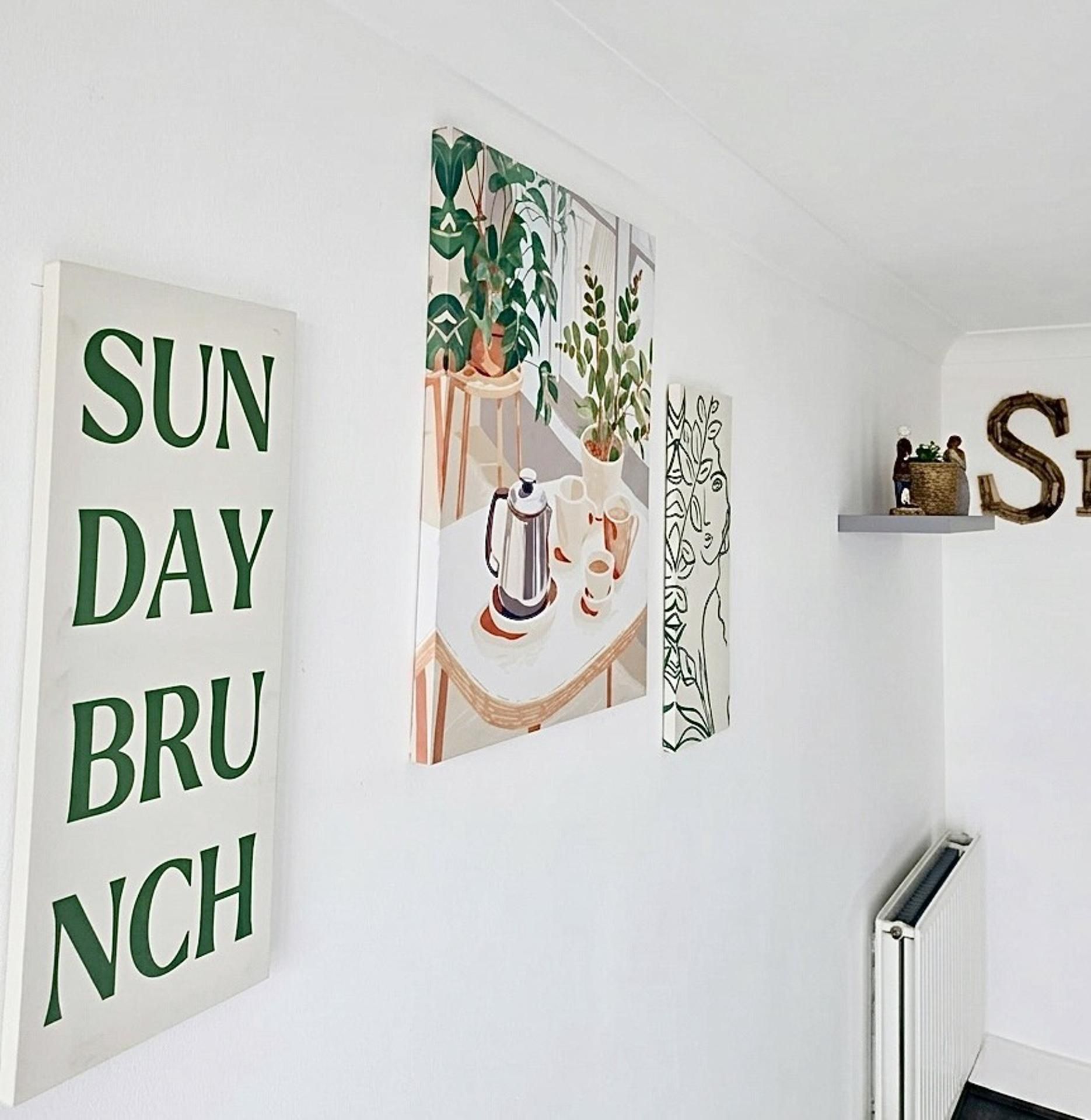 A wall with a large sign that reads 'SUN DAY BRUNCH' and three framed artworks.