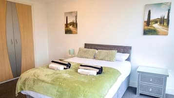Ein Hotelzimmer mit einem Bett, einem Nachttisch, einem Kleiderschrank und zwei Bildern an den Wänden.