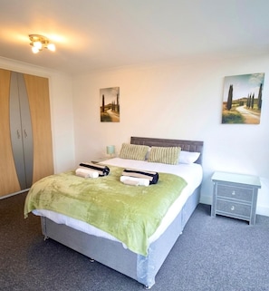 Una habitación de hotel con una cama, una mesita de noche, un armario y dos cuadros en las paredes.