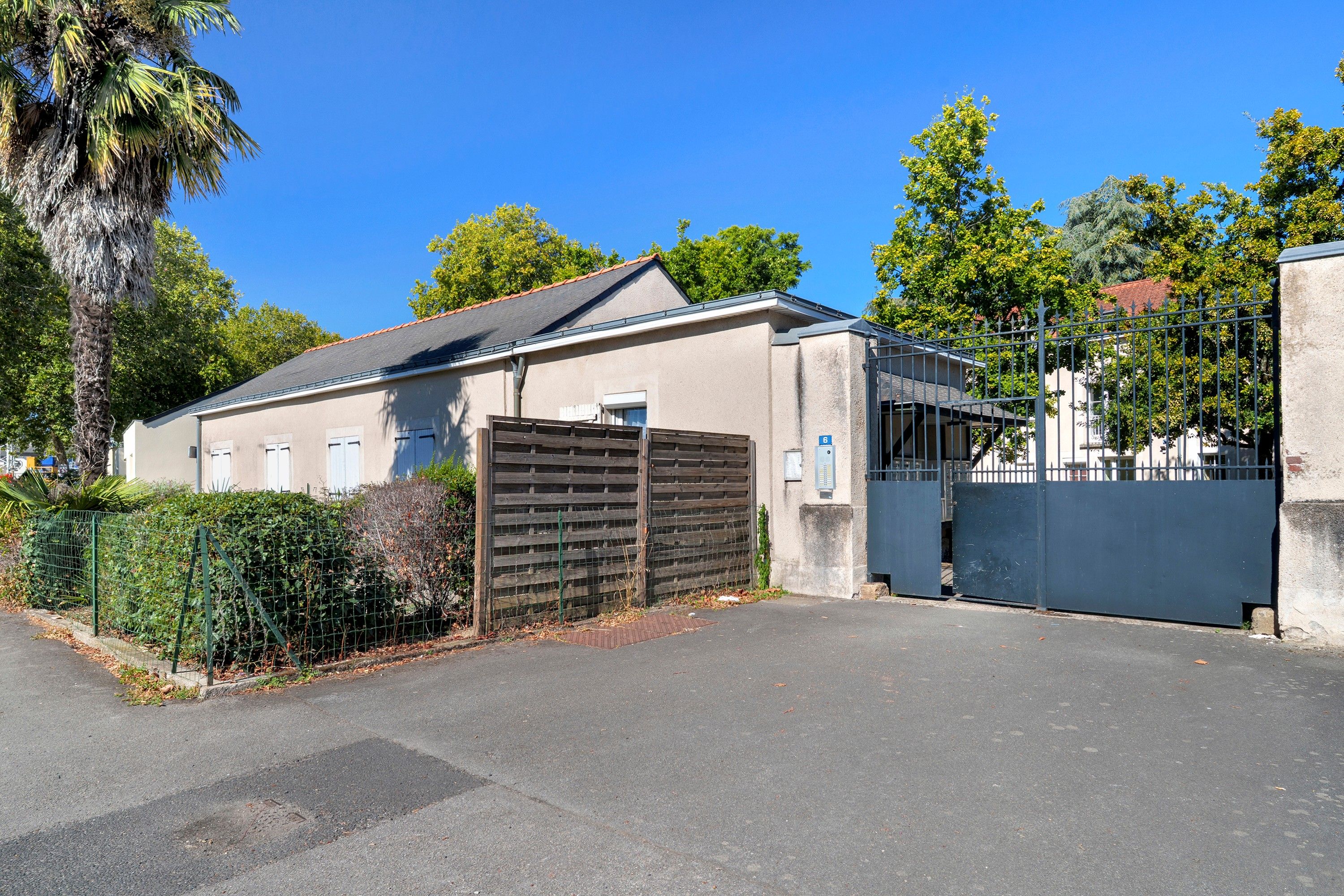 Un bâtiment doté d’une entrée sécurisée par un portail, d’un garage et surplombant un ciel dégagé.