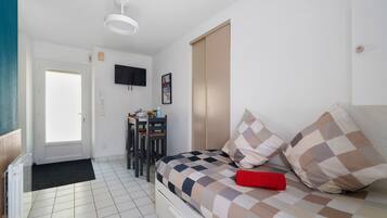 Un dormitorio con cama, escritorio, silla, televisor y radiador.