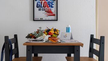 Una mesa con un cartel enmarco, una botella y una cesta de frutas.