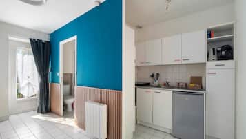 A modern kitchen with white cabinets, a dishwasher, and a blue accent wall.