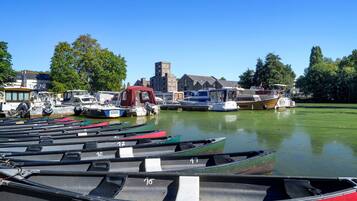 Un port de plaisance où sont amarrés divers bateaux, un bateau rouge au premier plan et un bâtiment historique en arrière-plan.
