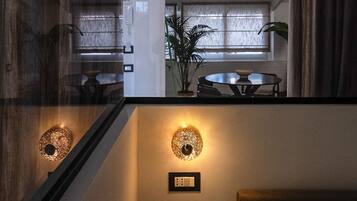 Une chambre d’hôtel avec un lit, une table de chevet sur laquelle se trouve un bol, un luminaire fixé au mur et une fenêtre avec des rideaux.