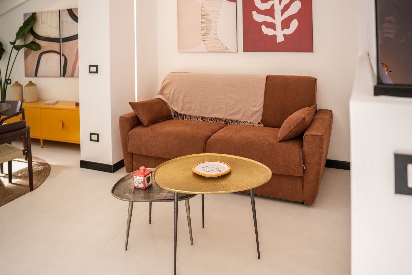 Ein Wohnzimmer mit einem braunen Sofa, einem kleinen runden Tisch und einem gelben Schrank.