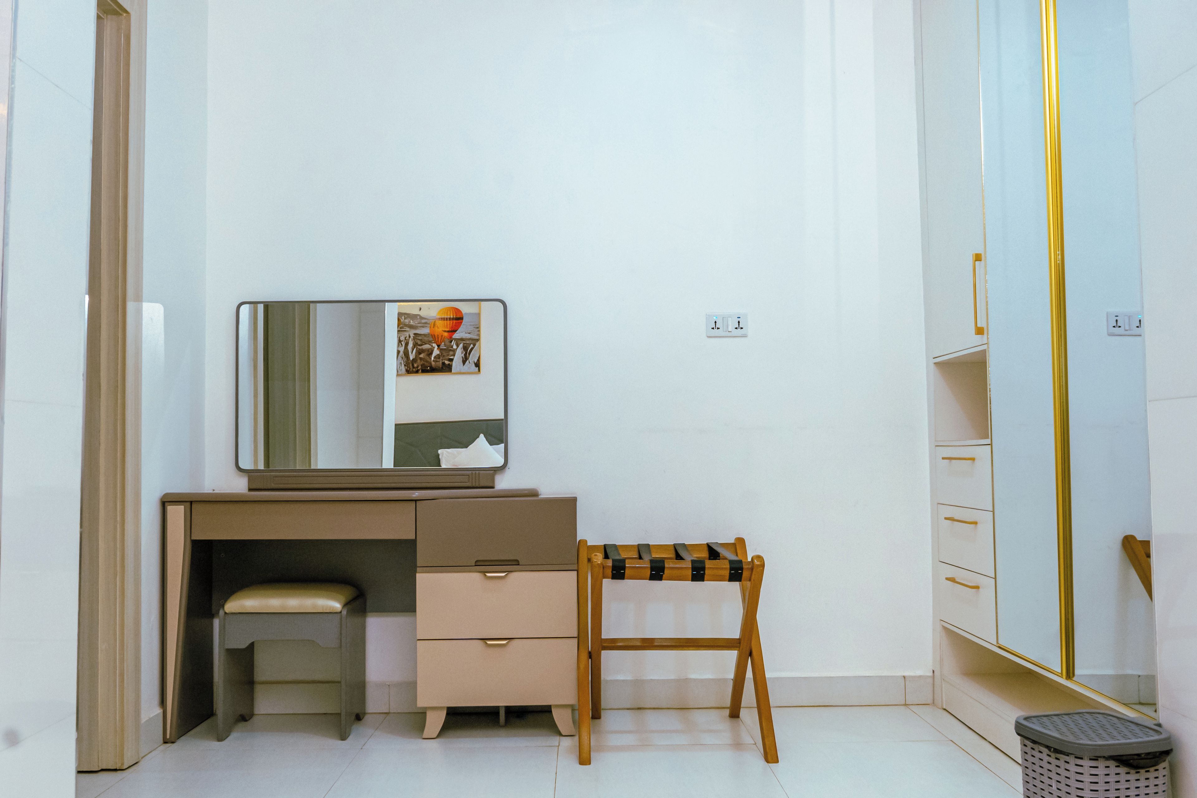 Un dormitorio pequeño y ordenado con una cama individual, una mesita de noche, un espejo y un armario.