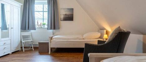 A bedroom with a bed, a chair, a desk, and a window with curtains.