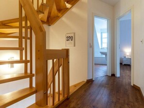Eine Holztreppe führt zu einem Raum mit einer weißen Wand und einem Schild mit der Aufschrift 'SPO'.