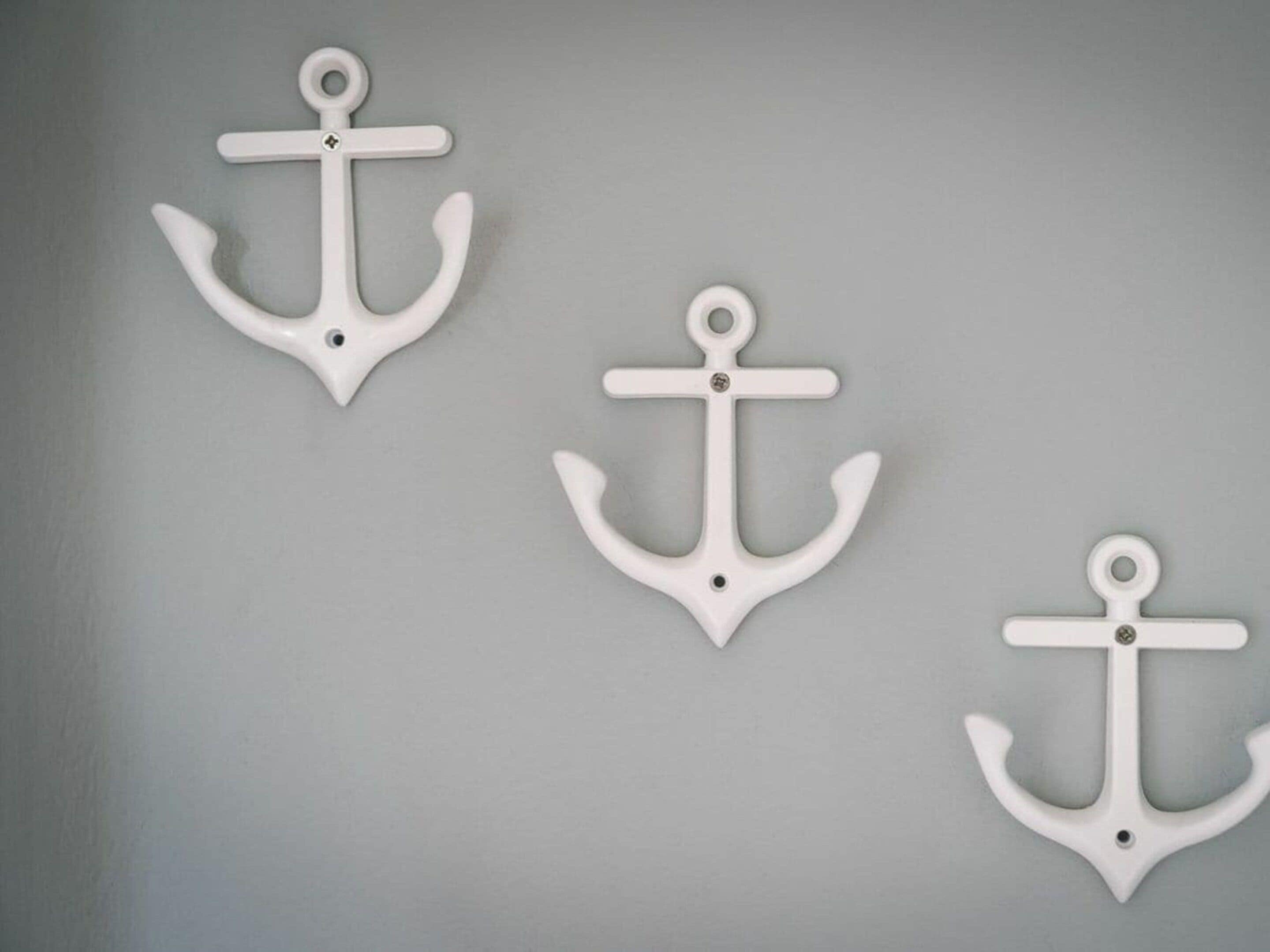 Three white anchors on a grey wall.