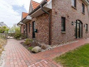 A brick building with a paved walkway and a gated entrance. - Holiday Home With 1 Bedroom (St. Peter-Ording)