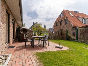 A patio area with a brick floor, a table, and chairs. - Holiday Home With 1 Bedroom (St. Peter-Ording)