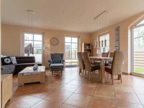 A spacious living area with a sofa, armchair, dining table, and chairs. - Holiday Home With 1 Bedroom (St. Peter-Ording)