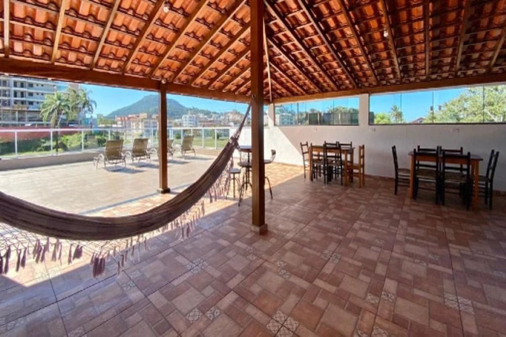 Une terrasse extérieure avec un sol carrelé, un hamac et un espace repas comprenant des chaises et des tables.