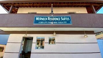 Een gebouw met een bordje waarop 'Werneck Residence Suites' staat, en contactnummers.