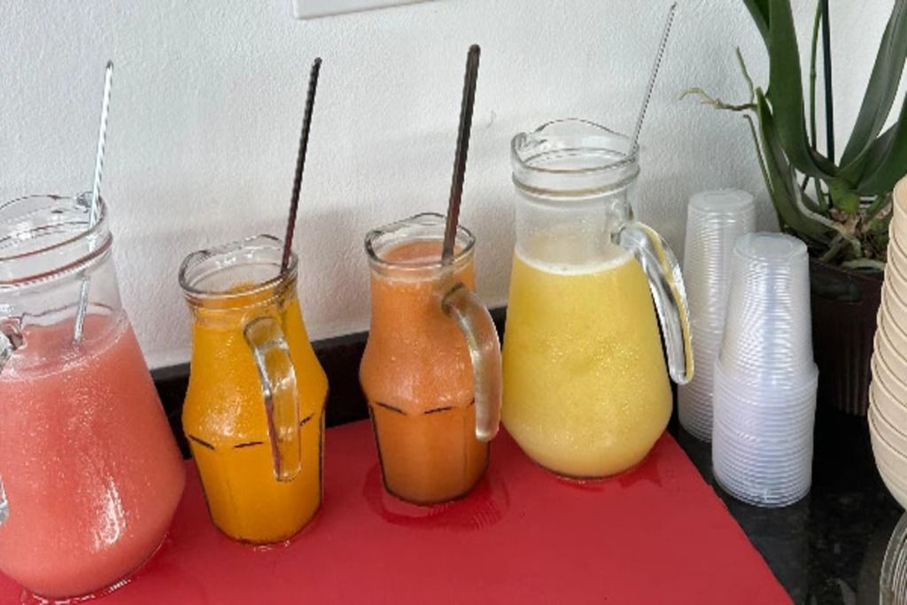 Four glass containers with straws, placed on a red surface.