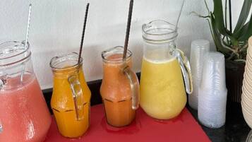 Four glass containers with straws, placed on a red surface.