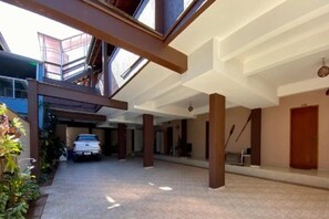Un vaste espace intérieur doté d’un haut plafond, un véhicule garé au fond, et un escalier menant à un niveau supérieur.