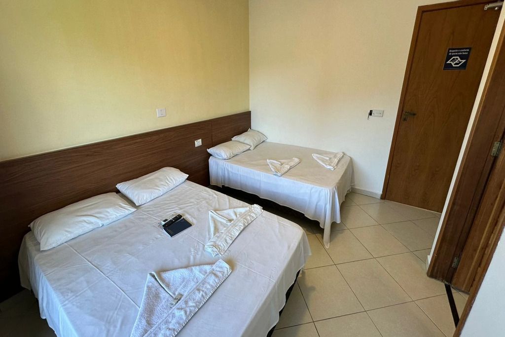 Ett hotellrum med två sängar, en sänggavel i trä och en dörr med en skylt.