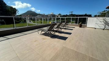 Een terras op het dak met ligbedden en uitzicht op een berg.
