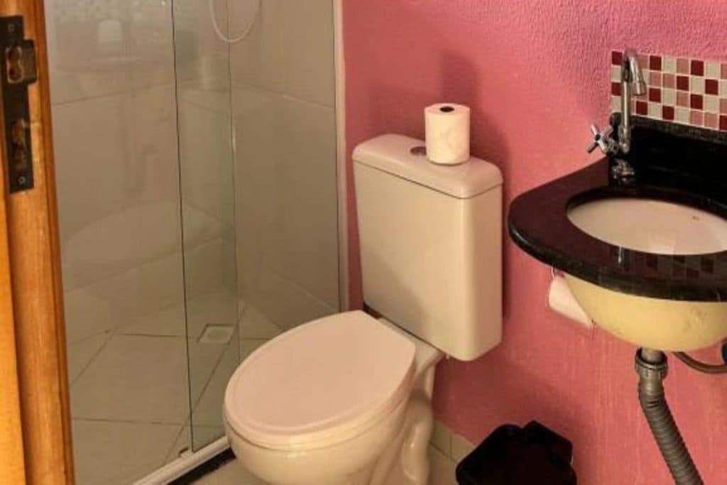 Casa de banho com sanita, chuveiro e lavatório.
