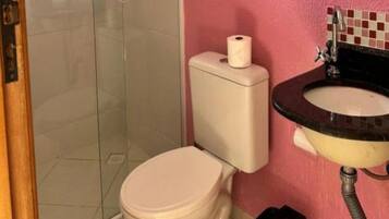 Casa de banho com sanita, chuveiro e lavatório.