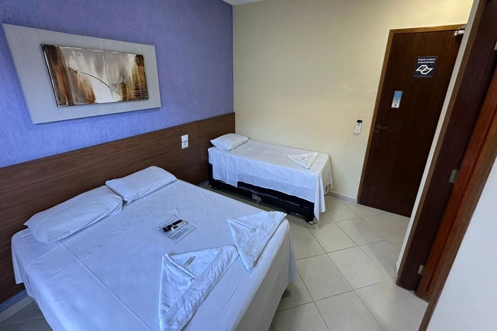 Una habitación de hotel con dos camas, una puerta con un letrero y una obra de arte colgada en la pared.