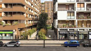 Un edificio residencial de varios pisos con balcones, un árbol visible y automóviles estacionados.