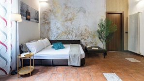 A hotel room with a bed, bedside tables, a lamp, a large abstract painting, a potted plant, and a radiator. - [Bocconi / Naviglio Pavese] Cozy Suite with 2 beds + Wi-Fi + A/C (Milano)