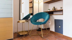 A teal chair with gold legs, a small round table, a mirror, a floor lamp, and a shelf with decorative items. - [Bocconi / Naviglio Pavese] Cozy Suite with 2 beds + Wi-Fi + A/C (Milano)