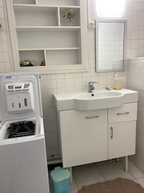 A bathroom with a white sink, mirror, and storage cabinets. There is a blue trash bin and a white toilet. - A 5-minute drive from the beach at Lac d'Hossegor Park, the golf course, and downtown (Soorts-Hossegor)