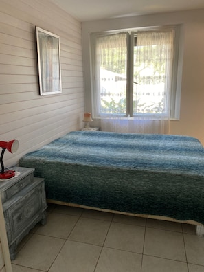 A room with a bed, a bedside table with a lamp, a window with curtains, and a wall-mounted mirror. - A 5-minute drive from the beach at Lac d'Hossegor Park, the golf course, and downtown (Soorts-Hossegor)