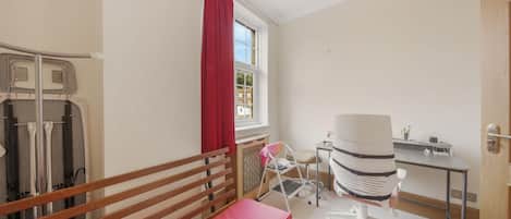 A bedroom with a bed, a desk, a chair, and a window with curtains.