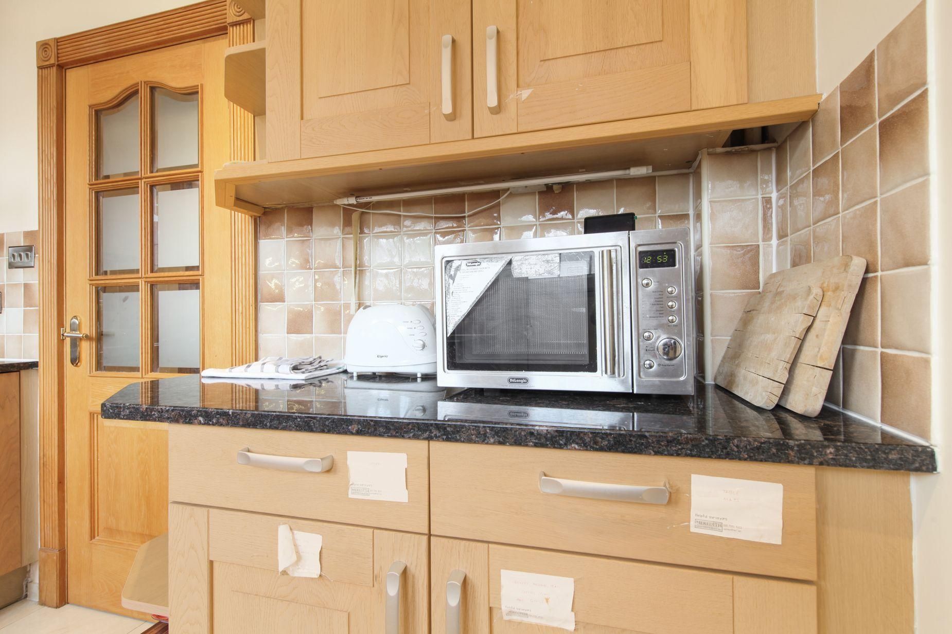 Una cucina con mobili in legno, un forno a microonde e un tostapane.