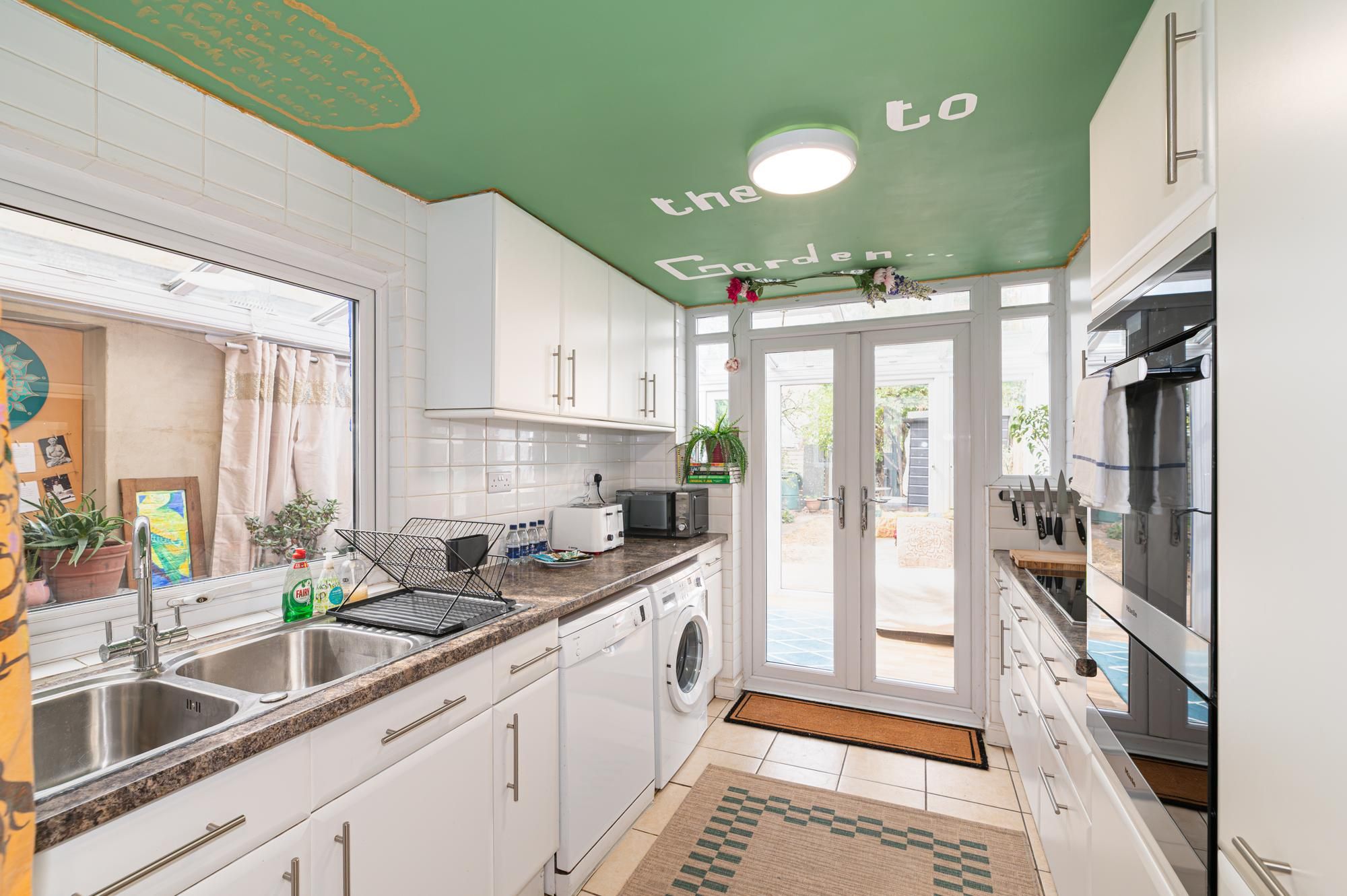 A kitchen with white cabinets, a built-in washing machine, a microwave, and a refrigerator.