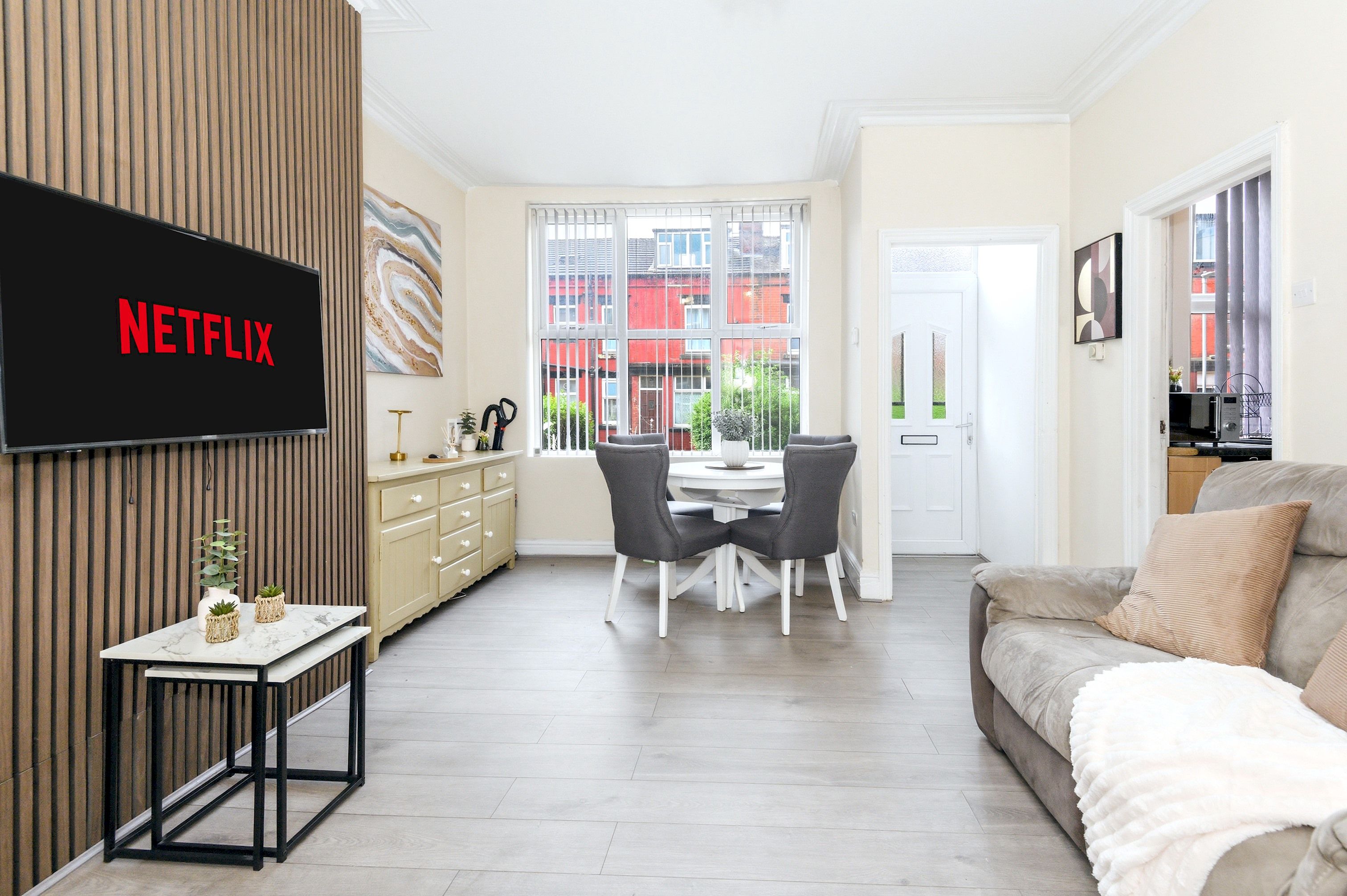 Ein modernes Wohnzimmer mit einem Flachbildfernseher, einem Essbereich mit Tisch und Stühlen sowie einer Couch.
