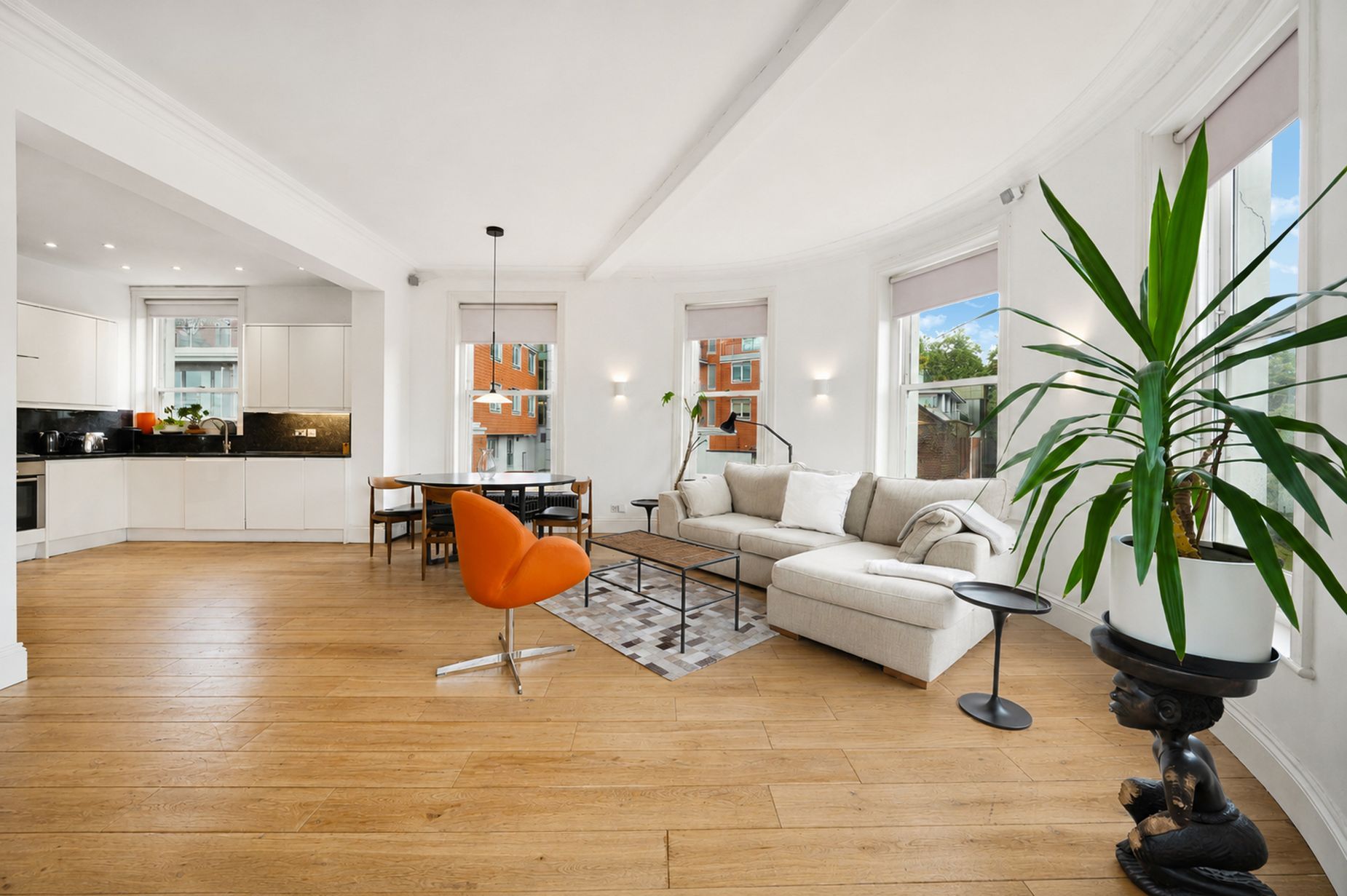 A spacious living area with a sofa, a dining table, and a kitchen in the background.