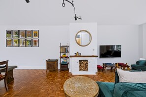 A living room with a herringbone floor, a fireplace, a bookshelf, and a television mounted on the wall. - Stylish Spacious Brighton Home | Parking & Garden - Pass the Keys (Brighton)