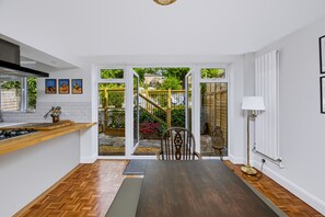 A modern kitchen with a wooden countertop, a dining area with a bench, and a view of a garden through glass doors. - Stylish Spacious Brighton Home | Parking & Garden - Pass the Keys (Brighton)