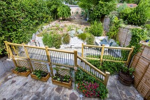 A garden with a wooden fence, stone steps, and various plants. - Stylish Spacious Brighton Home | Parking & Garden - Pass the Keys (Brighton)