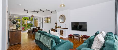 A spacious living room with a large sofa, a television, and a fireplace.
