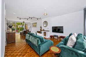 Ein geräumiges Wohnzimmer mit einer großen Couch, einem Fernseher und einem Kamin.
