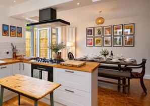 Een moderne keuken met een centraal eiland, een eethoek met een bank, en ingelijste foto's aan de muur.