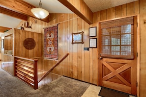 A wooden interior with a staircase, a patterned wall hanging, and a door with a window blind. - Cabin (10B) Arrow Lodge (Yosemite National Park)