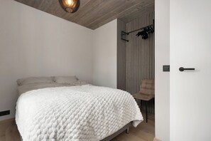 A bedroom with a bed, a chair, a door, and a wall with vertical lines. - Luxury Apt. Downtown Reykjavik - Best Location (Reykjavík)