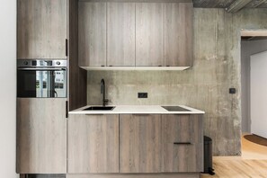A modern kitchen with wooden cabinetry, a stainless steel sink, and a built-in oven. - Luxury Apt. Downtown Reykjavik - Best Location (Reykjavík)